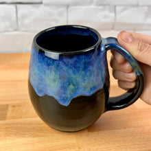 Load image into Gallery viewer, Aurora Borealis Mugs. each one is different. northwest style coffee mug thrown Red Stoneware, with large pulled handle. black glaze base with swirls of blue, turuoise, and hints of purple, reminiscent of the Aurora Borealis.