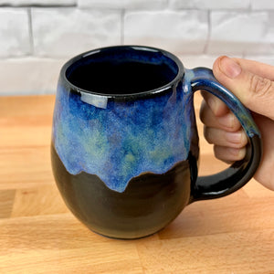 Aurora Borealis Mugs. each one is different. northwest style coffee mug thrown Red Stoneware, with large pulled handle. black glaze base with swirls of blue, turuoise, and hints of purple, reminiscent of the Aurora Borealis.