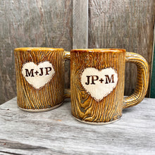 Load image into Gallery viewer, Large custom coffee mugs with lumberjack, woodgrain texture pattern impressed and carved in for texture you can feel. the mugs have a heart carved into them with initials, like lovers would carve into a tree