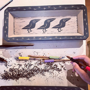 work in process: an image of the artist carving crow patterns into a 'leather hard" clay paltter using diamondcore carving tools. each platter is handcrafted and hand carved in the traditional sgraffito process. 