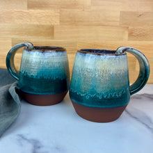 Load image into Gallery viewer, two Forest Mist Mugs. each is a  handmade ceramic mug with a pulled handle, featuring a glaze that transitions from speckled white at the top to a deep teal over a deep red-brown stoneware clay. 