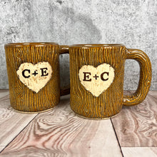 Load image into Gallery viewer, Large custom coffee mugs with lumberjack, woodgrain pattern impressed and carved in for texture you can feel. the mugs have a heart carved into them with initials, like lovers would carve into a tree