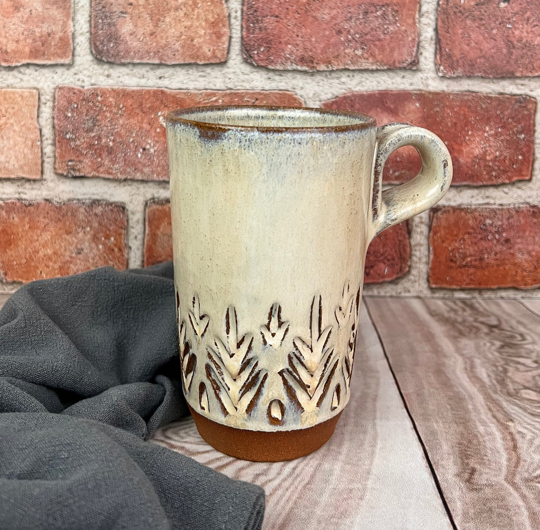Travel mug in red stoneware clay, hand carved tree pattern, glazed in speckled white glaze. (no lid)