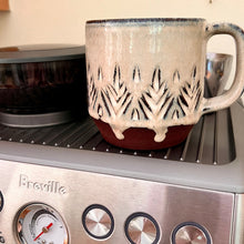Load image into Gallery viewer, hand carved mug, warming on the Breville. This mug has some perfect glaze drips