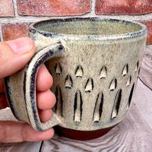 Load image into Gallery viewer, The artist holding a carved mug, showing the three finger  pulled handle with groovy thumb groove.
