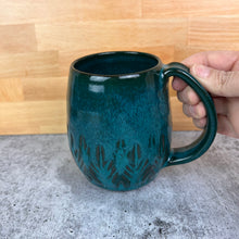 Load image into Gallery viewer, Beautiful, vibrant teal glaze on a hand carved northwest mug. the carvings allow the glaze to show through a bit at the edges, bringing variation to the glaze.