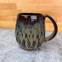 Load image into Gallery viewer, Beautiful, caramel glaze on a wheel thrown, hand carved northwest mug. the carvings allow the glaze to show through a bit at the edges, bringing variation to the glaze. this glaze also shows the deep red clay color beneath it.
