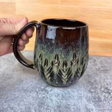 Load image into Gallery viewer, Beautiful, caramel glaze on a wheel thrown, hand carved northwest mug. the carvings allow the glaze to show through a bit at the edges, bringing variation to the glaze. this glaze also shows the deep red clay color beneath it.