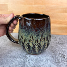 Load image into Gallery viewer, Beautiful, caramel glaze on a wheel thrown, hand carved northwest mug. the carvings allow the glaze to show through a bit at the edges, bringing variation to the glaze. this glaze also shows the deep red clay color beneath it.