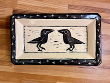 Load image into Gallery viewer, crow or raven carved pottery platter. crows are sgraffito carved into the center with footprints around the edge. stoneware, black on white clay.