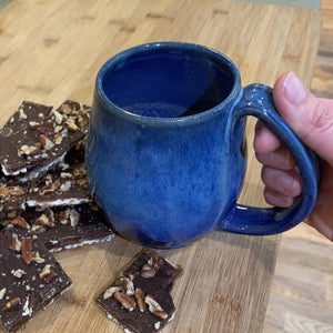Deep Blue mug, northwest style coffee mug thrown pottery, with large pulled handle with groovy thumb groove. shown with matzah roca cookies