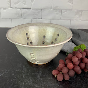 A wheel thrown pottery colander in speckled white glaze. 8" diameter colander