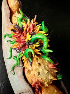 detail image of my Seed Pod Sculpture, "Sprouting Pod". Sculpted from stoneware it shows the dry outer husk in contrast with the vibrant blooming seeds which are growing and sprouting from within.