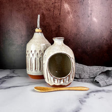 Load image into Gallery viewer, Salt Cellar, also known as a salt well or salt pig. shown here with matching Olive oil cruet. Wheel thrown and carved. comes with a bamboo spoon and a starter sea salt packet.. Thrown in a red stoneware clay, with a handled top, and carved by hand. the white glaze accentuates the carved pattern where the red clay shows through. Fern Street Pottery