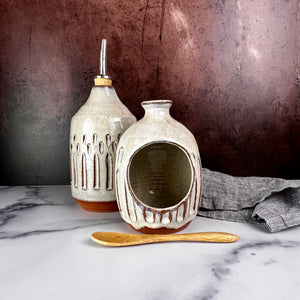Salt Cellar, also known as a salt well or salt pig. shown here with matching Olive oil cruet. Wheel thrown and carved. comes with a bamboo spoon and a starter sea salt packet.. Thrown in a red stoneware clay, with a handled top, and carved by hand. the white glaze accentuates the carved pattern where the red clay shows through. Fern Street Pottery