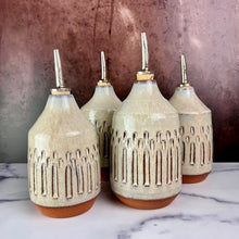 Load image into Gallery viewer, Olive oil cruets. Wheel thrown and carved. cork stopper  for smooth pouring. Thrown in a red stoneware clay and carved by hand. the white glaze accentuates the carved pattern where the red clay shows through.
