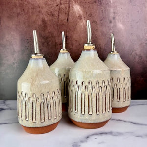 Olive oil cruets. Wheel thrown and carved. cork stopper  for smooth pouring. Thrown in a red stoneware clay and carved by hand. the white glaze accentuates the carved pattern where the red clay shows through.