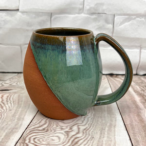 Wheel thrown and hand crafted in red-brown stonware clay, this angle dipped mug is featured in a drippy moss green glaze. beautiful color and textures. holds 14-16 oz. Fern Street Pottery