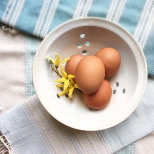 Berry colander in pure white, shown with french linens and fresh eggs