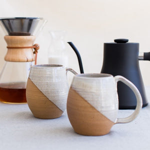 angle dipped mugs in speckled white glaze. wheel thrown in stoneware. shown with contemporary, classic coffee products. Fern Street Pottery