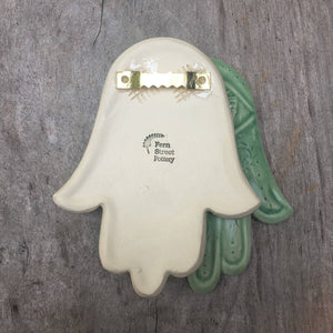 hanging hamsa hand, shwoing the sawtooth hanger on back