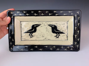 crow or raven carved pottery platter. crows are sgraffito carved into the center with footprints around the edge. stoneware, black on white clay.